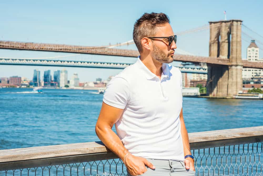 This is a man wearing a white polo shirt by the water.