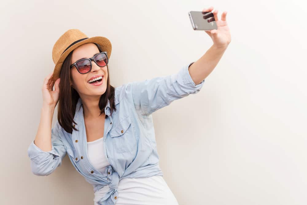 A woman wearing a brown woven fedora with her casual clothes.