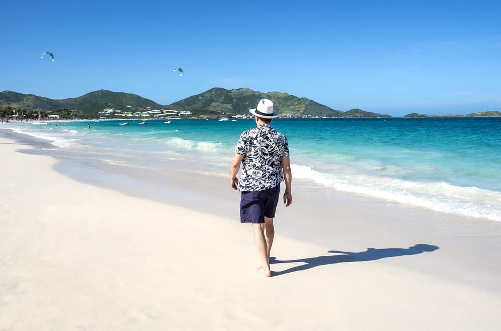 A man wearing a Hawaiian shirt at the beach.
