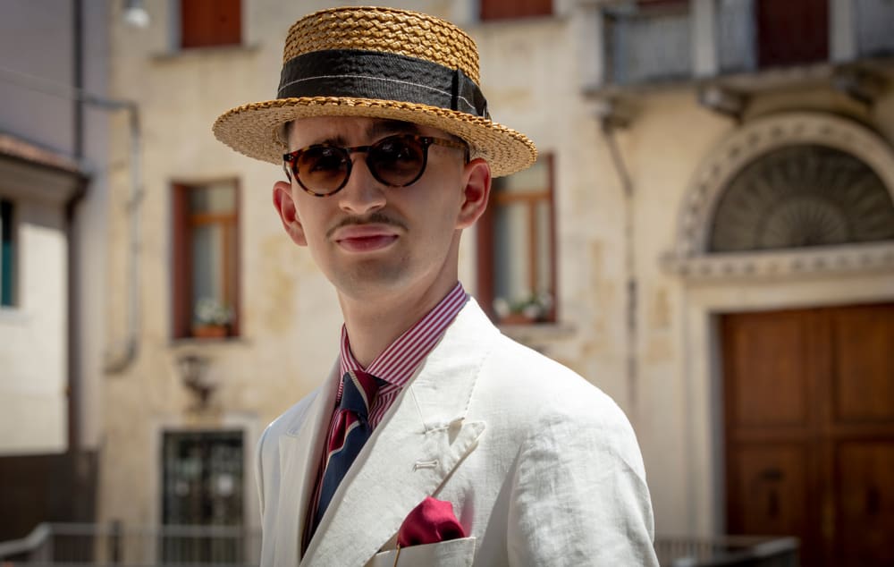 A man wearing a suit and a straw boater hat.