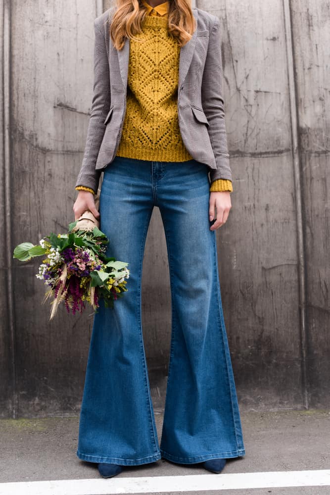 This is a close look at a woman wearing long flared denim jeans.