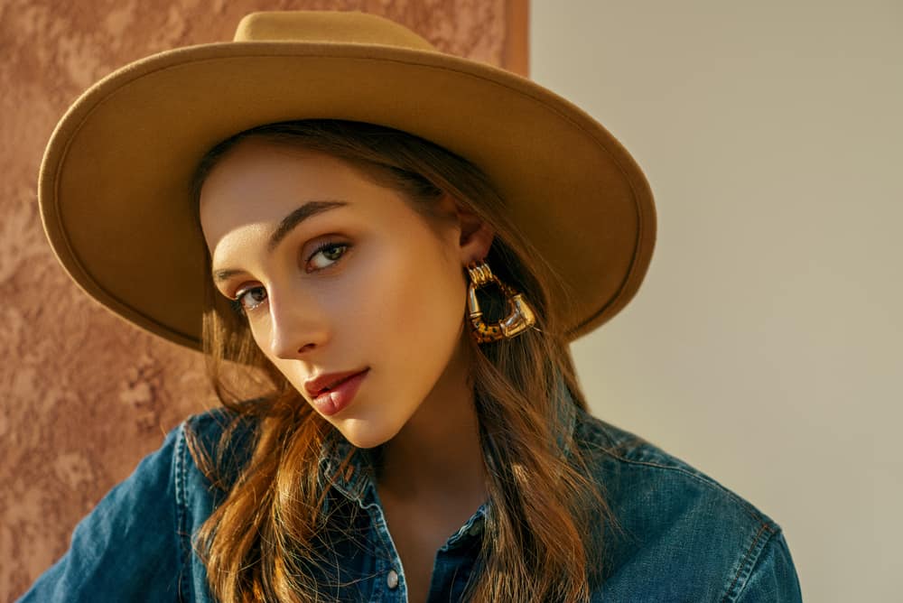 A close look at a woman wearing a brown wide-brim fedora.