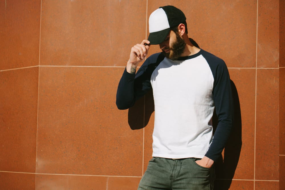 A man wearing a baseball cap and a long sleeve baseball shirt.