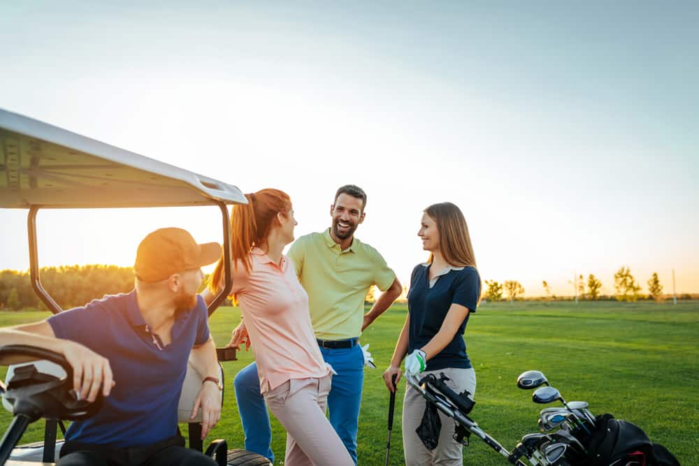 A group of friends wearing golf shirts while playing golf.