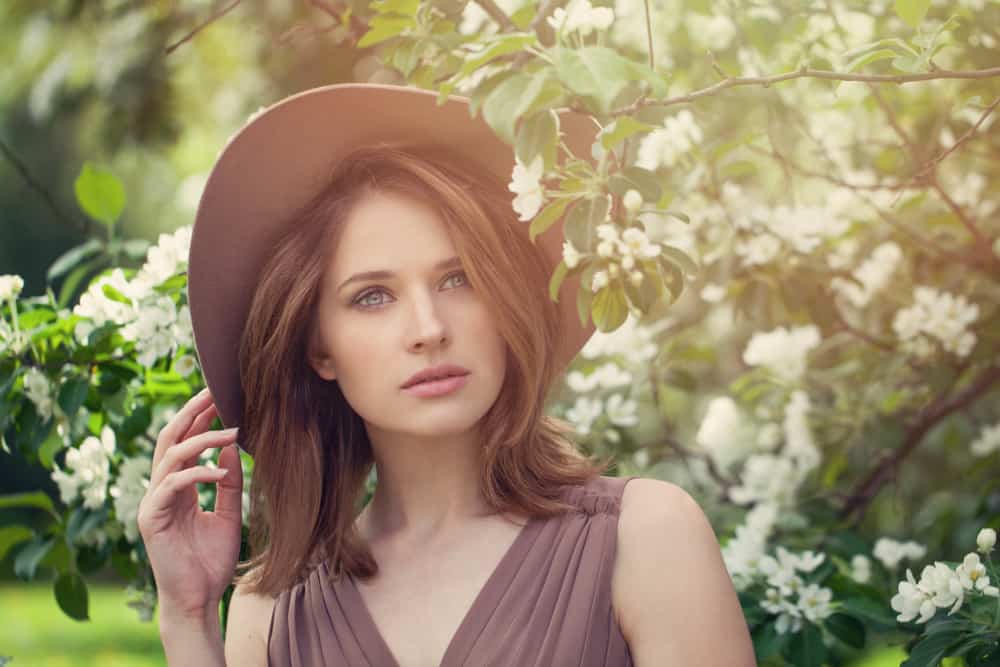 A woman wearing a dress with her brown fedora.