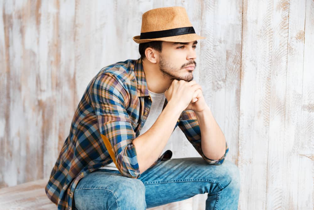 A man wearing a casual fedora with his outfit.
