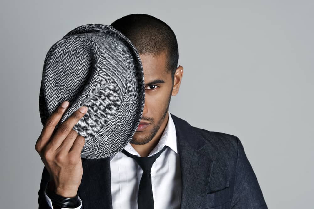A man wearing a suit with a gray fedora hat.