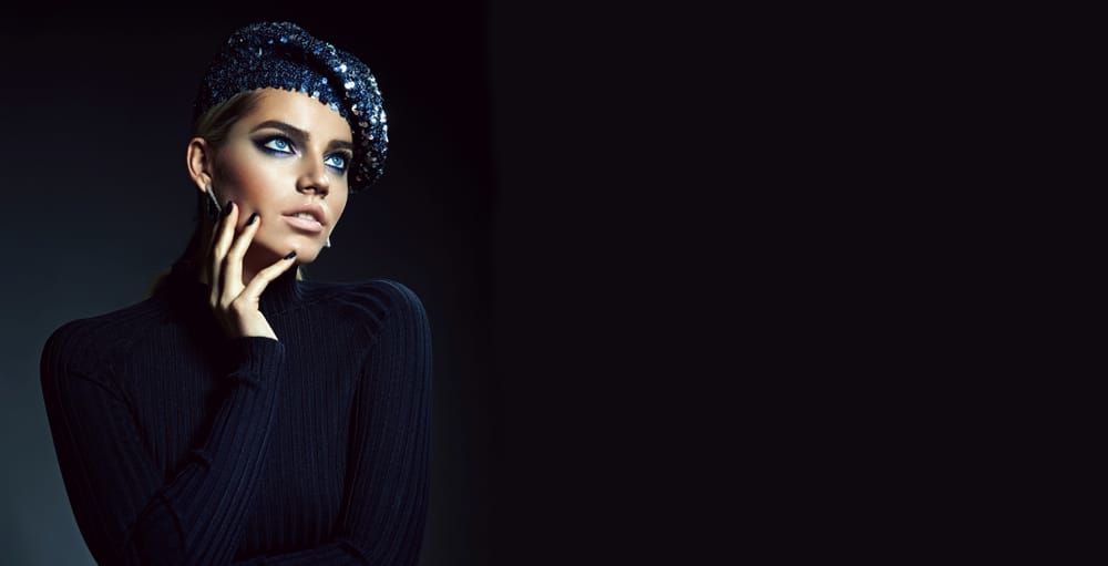 This is a woman wearing a black sequined beret to match her black shirt.