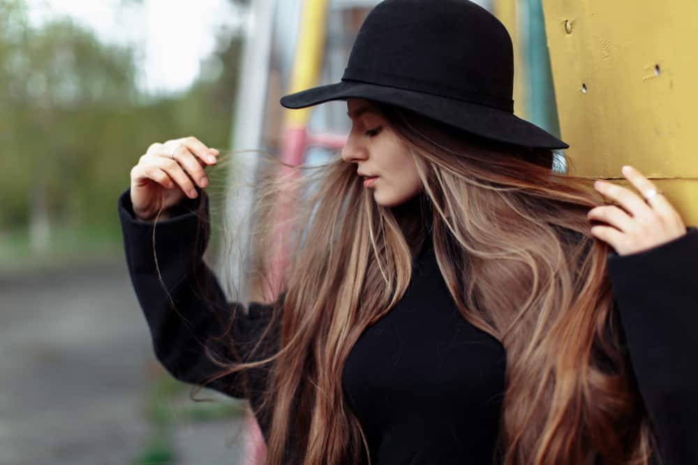 A woman wearing a black sweater and a matching black fedora.