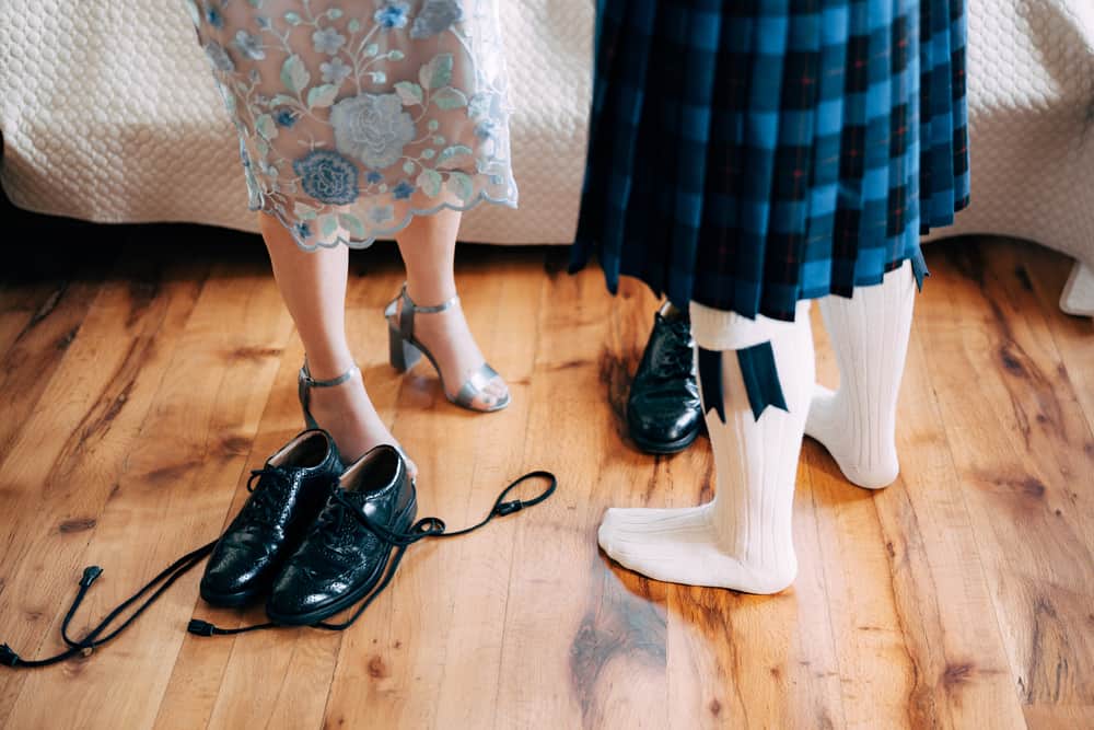A groom wearing a traditional kilt getting ready.