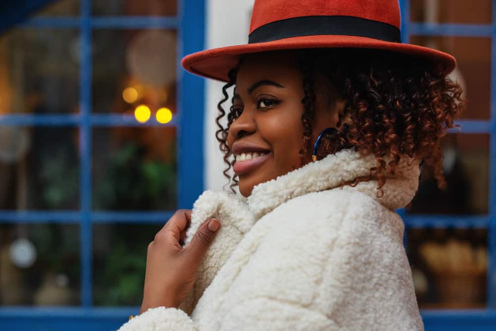 A woman wearing a white fur coat with her red fedora.