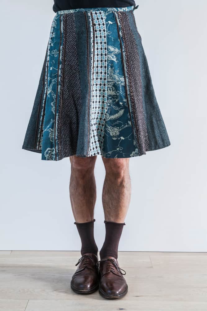A man wearing a patterned knee-length skirt.
