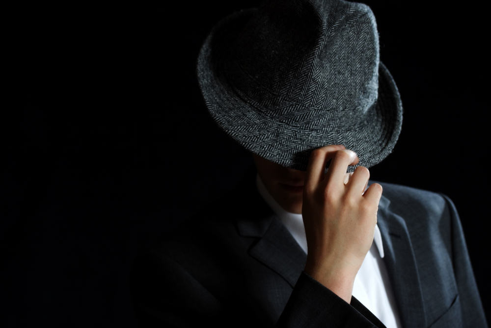 This is a man wearing a dark gray trilby hat.