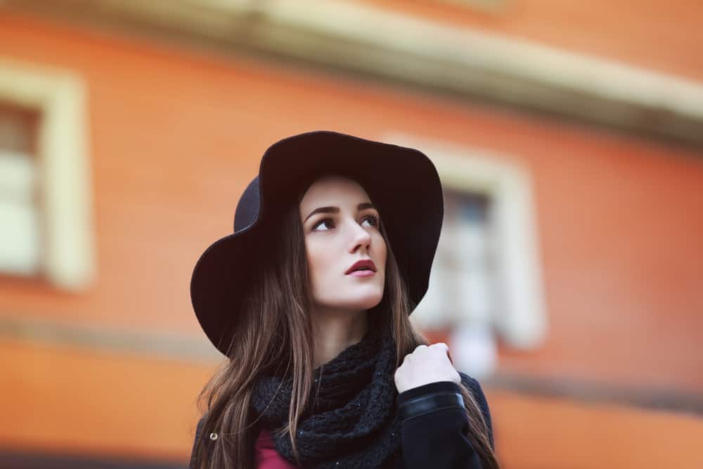A close look at a woman wearing a dark hat and a dark scarf.