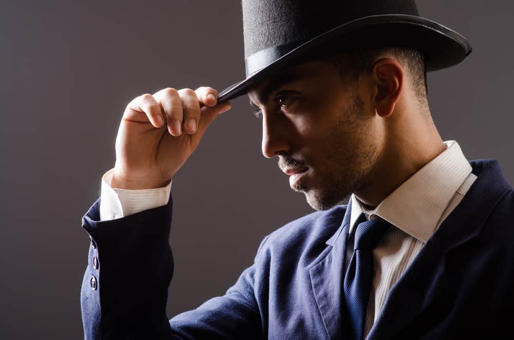 A man wearing a dark suit and a fedora.