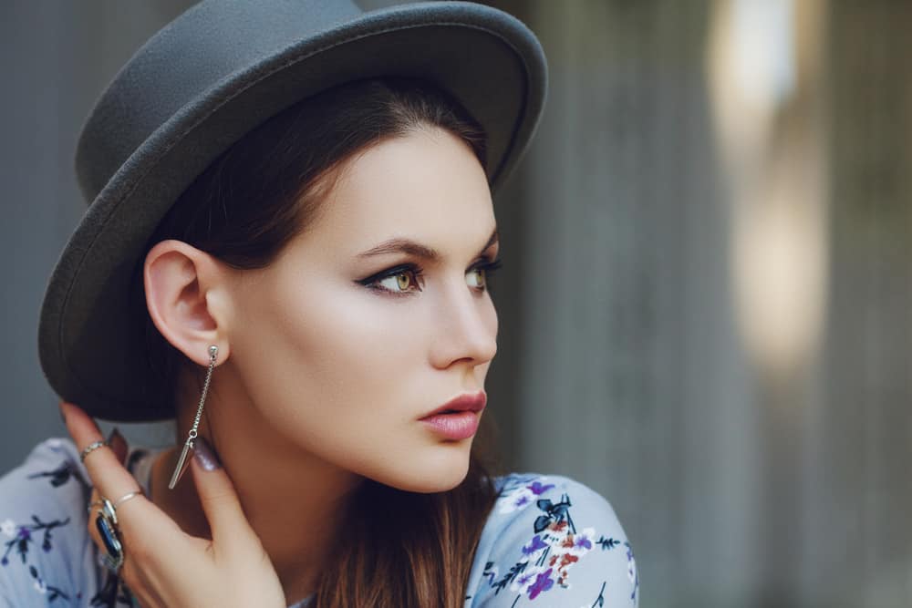 A woman wearing a floral blouse with fedora.