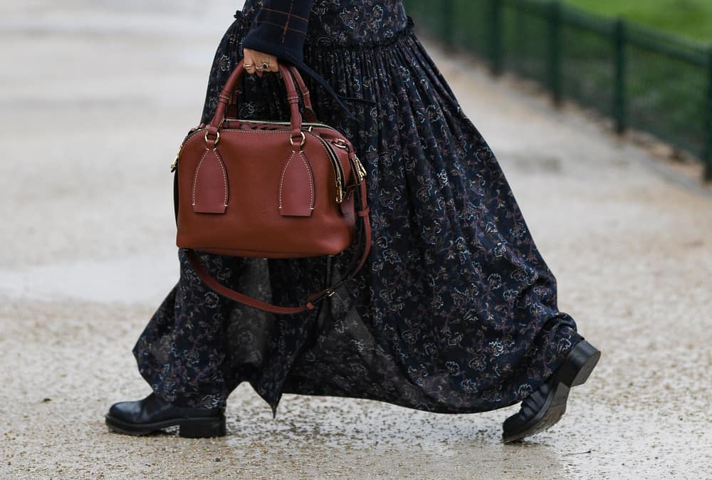 This is a woman wearing a floral maxi skirt with her black leather heel boots.