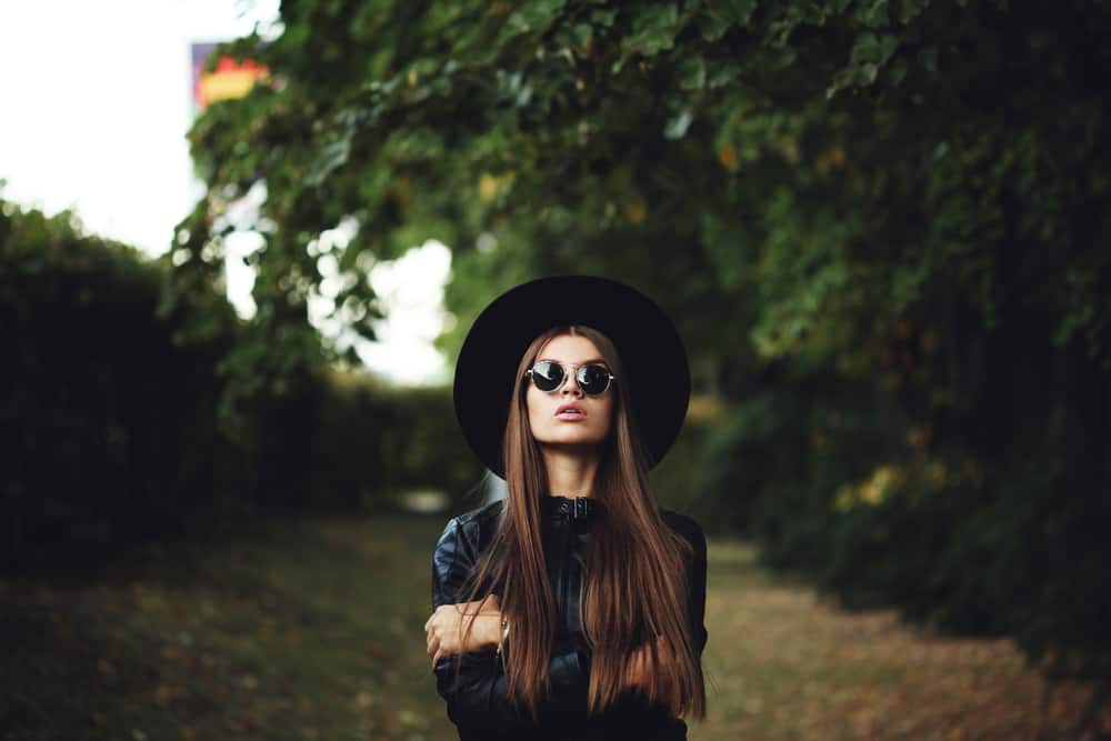 A woman wearing a black leather jacket and a matching black fedora.