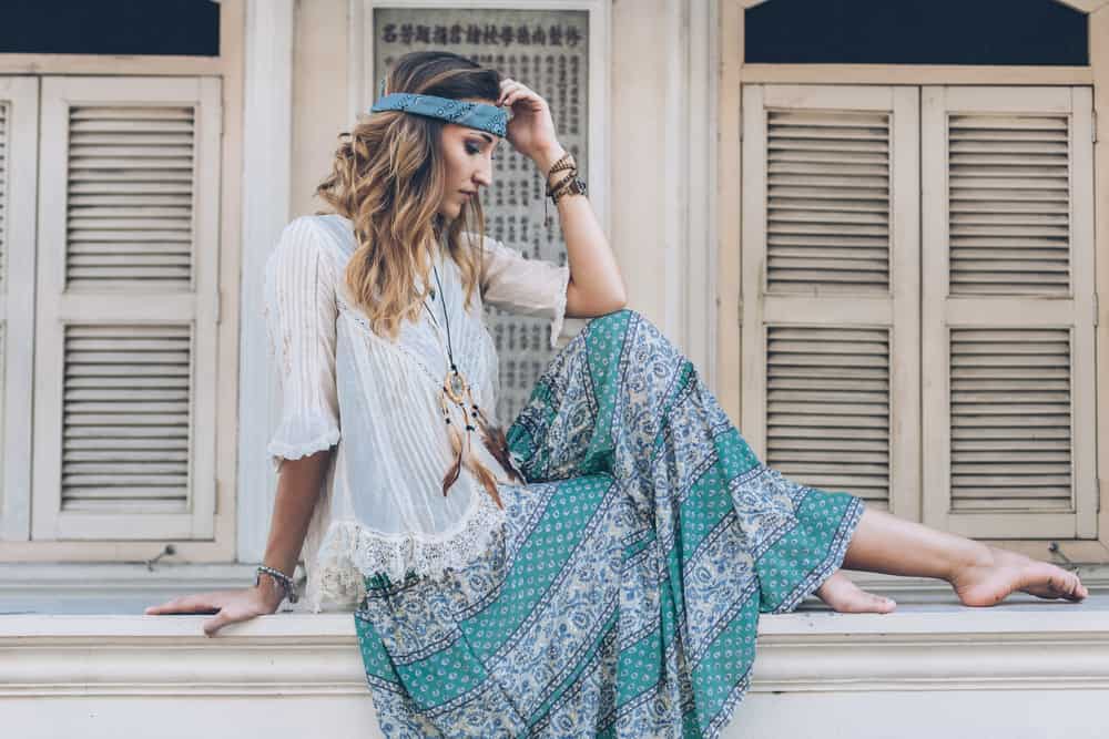 This is a woman wearing a white sheer blouse with her patterned maxi skirt that matches her headband.