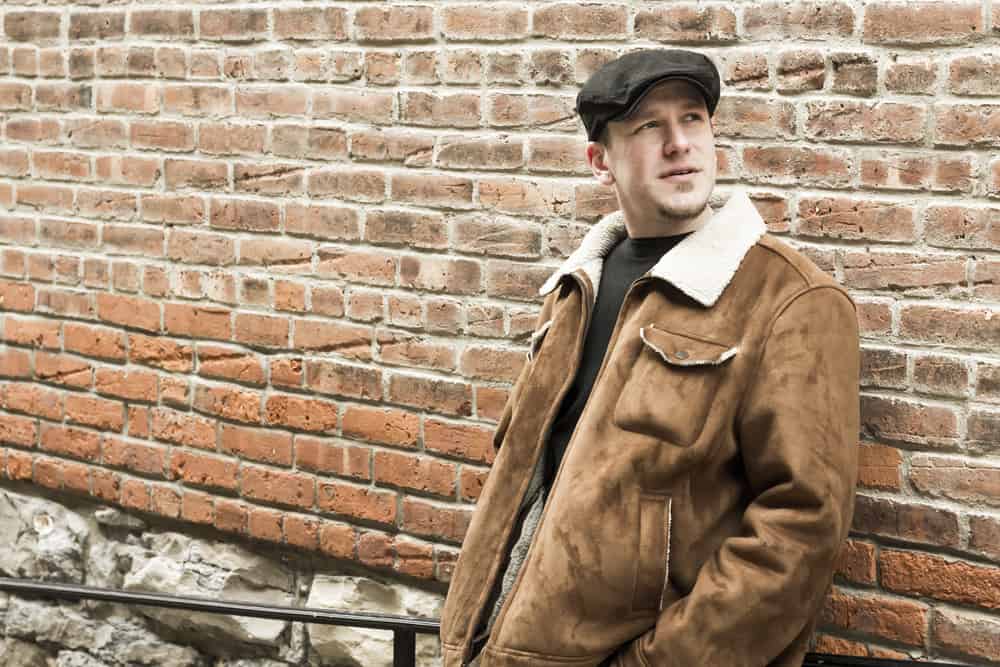 This is a man wearing a brown aviator jacket and newsboy cap.