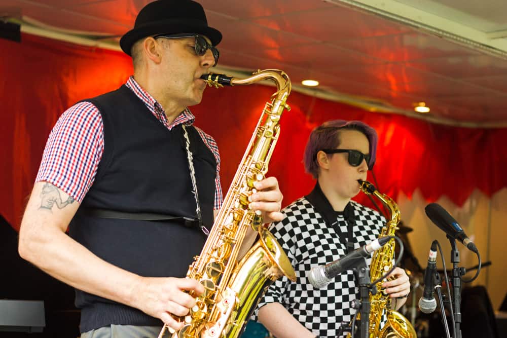 This is a close look at a performing saxophone player wearing a pork pie hat.