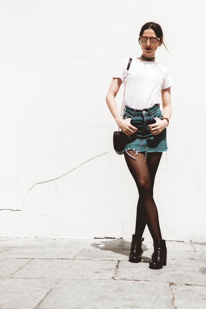 This is a fashionable woman wearing a white shirt, denim skirt and leggings.